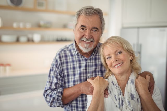 Senior couple embracing and smiling in a modern kitchen. Perfect for use in advertisements, articles, and websites related to senior living, retirement, family life, and health care. Ideal for promoting products and services aimed at elderly people, showcasing happy and healthy relationships, and illustrating concepts of love and togetherness in later life.