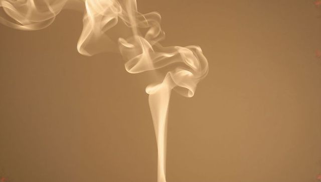 Elegant beige smoke ribbon rising in minimalist studio backdrop with wispy curled tendrils