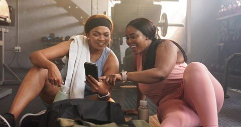 Two Women Laughing and Checking Smartphone After Gym Workout, Friendship and Fitness