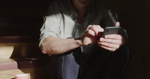 Man Relaxing on Stairs with Coffee and Smartphone