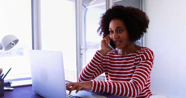 Focused African American Woman Working on Laptop While Talking on Phone - Download Free Stock Images Pikwizard.com