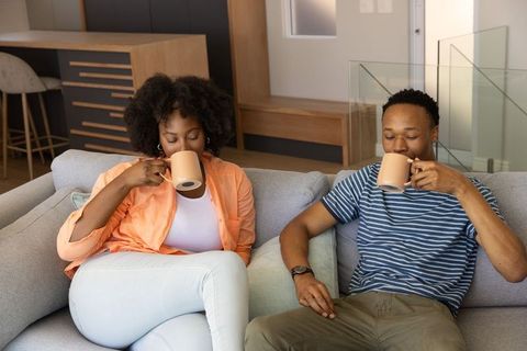 Couple Relaxing on Sofa Drinking Coffee Together in Modern Open-Plan Living Room Morning