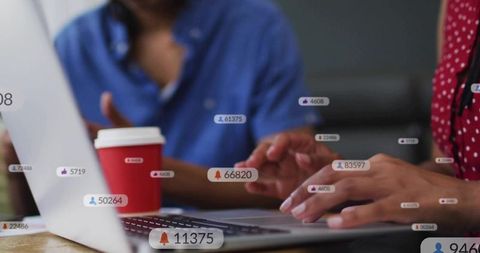 Hands typing on laptop with social notifications and coffee cup, collaborative workspace