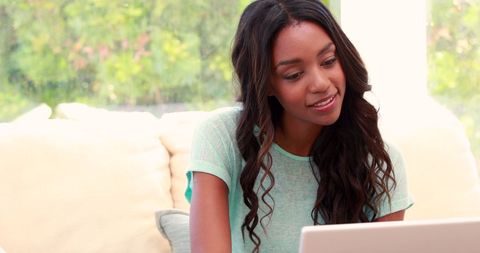 Woman Smiling While Working on Laptop at Home