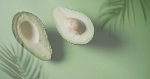 Halved avocado on green with tropical vibe