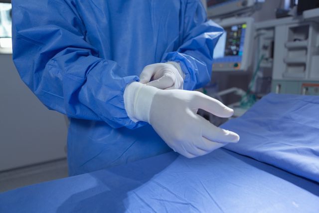 Front view Male surgeon wearing surgical gloves while standing in operation room at hospital