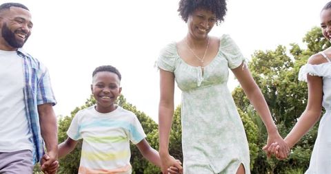 Family Enjoying Leisure Time in Green Garden with Kids Holding Hands