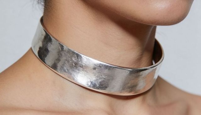 Wide silver metal choker on bare neck closeup, minimalist luxury jewelry on adult woman