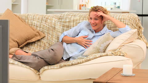 Casual Woman Joyfully Relaxing While Watching TV at Home