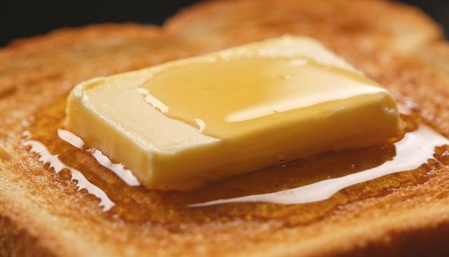 Melting butter pat and honey drizzling over golden toasted bread macro breakfast closeup