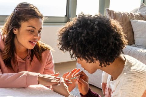 Multicultural friends painting nails at home in sunlit cozy manicure and friendship