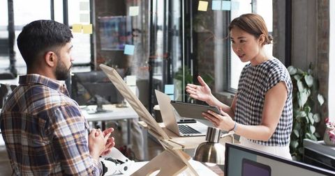 Asian woman discussing project on tablet with male colleague