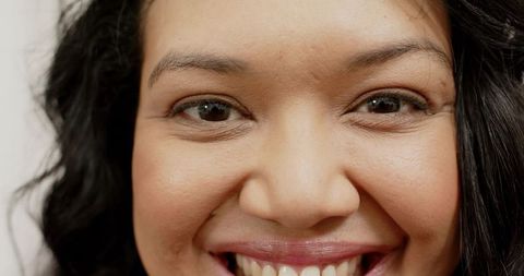 Close-up smiling woman headshot showing eyes, lips, teeth, confident warm expression