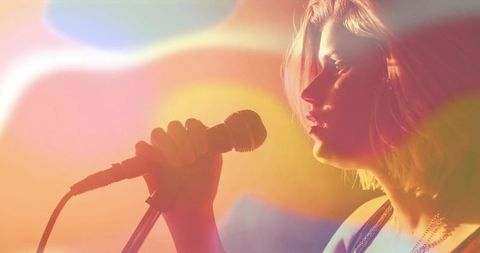 Teen singer emoting under warm stage lights holding wired microphone for concert promo