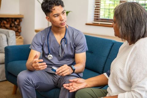 Young Nurse Discussing Health with Senior Patient on Blue Couch