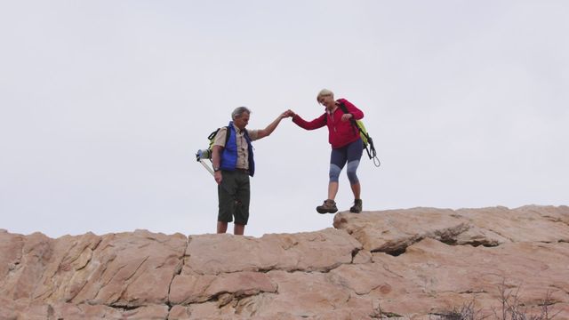 Senior couple exploring rocky terrain, highlighting the importance of companionship and teamwork. Ideal for promoting healthy lifestyle, fitness activities for retirees, and adventure tourism. Perfect for use in advertisements focusing on active aging, nature treks, or senior community outreach programs.