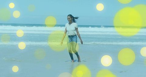 Woman Enjoying Serene Beach Walk with Sun-Soaked Ocean Waves