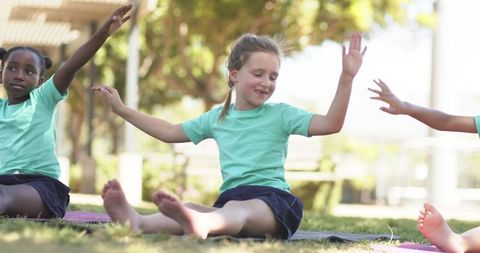 Diverse school-age children practicing outdoor yoga and stretching on grassy schoolyard mats