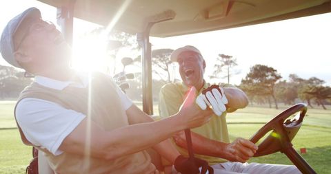 Two friends enjoying a laugh in golf buggy on sunny day