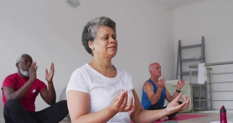 Mature woman practicing seated meditation in group yoga class for mindfulness and calm