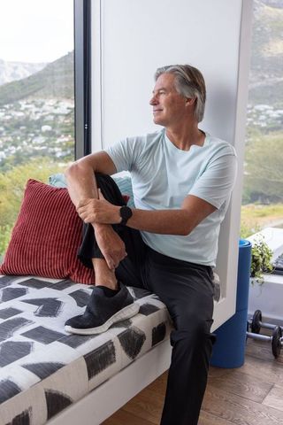 Mature man sitting on window bench looking out at scenic mountain view