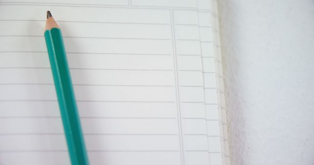 Green pencil resting on a blank notebook page showing defined lined spaces offers a versatile tool for storytelling about education, planning, and creativity. This imagery is ideal for content related to academics, organization habits, or office supplies marketing.