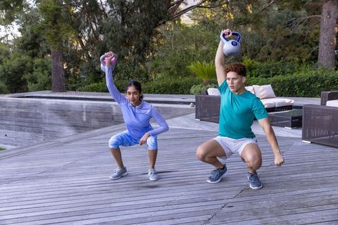 Diverse workout partners training with kettlebells outdoor