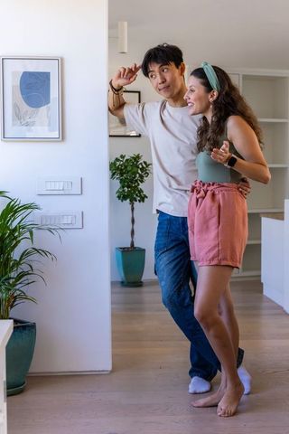 Young diverse couple admiring wall art and pointing in bright modern minimalist apartment