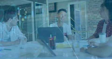 Startup Team Collaborating Around Laptop with Data Overlay in Modern Workspace
