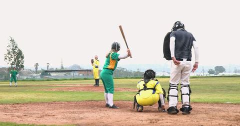 Softball game action on community field with diverse team