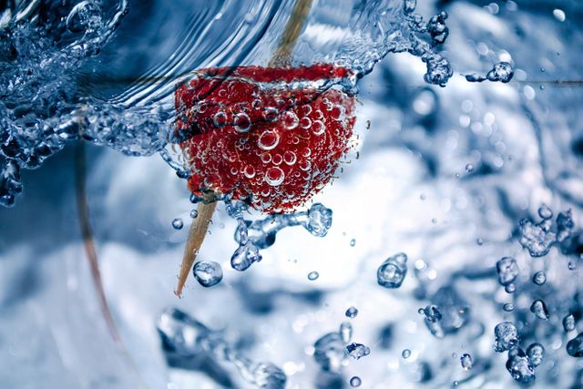 Red berry submerged underwater surrounded by bubbles and splashes. High detail captures bubbles forming around the fruit, creating a refreshing and dynamic scene. Perfect for promoting healthy eating, refreshing beverages, or summer-themed designs. Ideal for use in food and beverage campaigns, wellness articles, and lifestyle blogs.