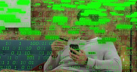 Man on blue sofa tapping smartphone with stylus layered with green binary code for cyber tech