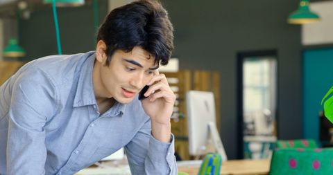 Young professional engaging in phone conversation at casual workplace