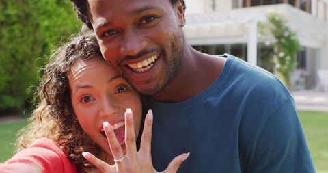 Happy couple celebrating engagement with selfie outdoors