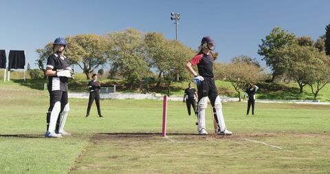 Female Cricket Players Competing on Field with Bright Pink Stumps