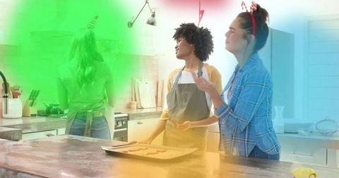 Friends baking holiday cookies on kitchen island, mixing dough, laughing, festive fun