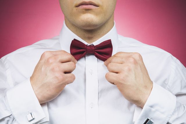Man Adjusting Red Bow Tie Against Pink Background - Download Free Stock Photos Pikwizard.com