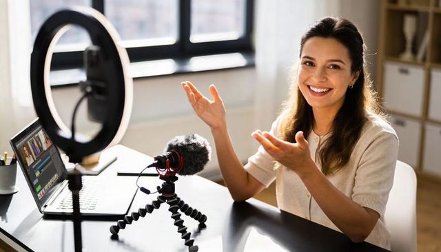 Friendly female content creator smiling and gesturing during live stream in home studio