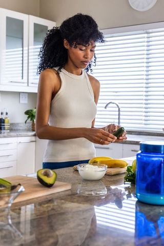 African american woman preparing avocado and banana breakfast in modern kitchen