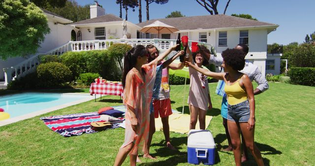 Diverse group of friends making a toast at a pool party. Hanging out and relaxing outdoors in summer.