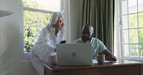 Couple planning wedding at home with laptop and smartphone