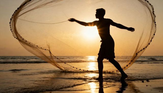Silhouette fisherman casting circular net at golden hour sunset on tropical beach