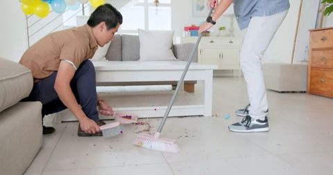 Men Sweeping Confetti in Living Room After Celebration