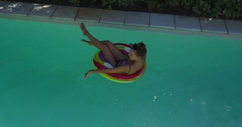 Woman relaxing on inflatable ring in turquoise pool
