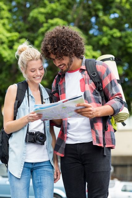 Young couple enjoying an outdoor adventure, using a map to navigate their surroundings. Ideal for travel blogs, tourism advertisements, adventure-themed content, and promotional materials for outdoor activities.