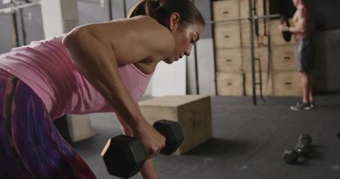 Focused Woman Lifting Dumbbell at Gym for Strength Training