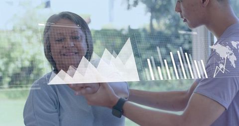 Caregiver assisting senior woman with wearable smartwatch and projected health charts