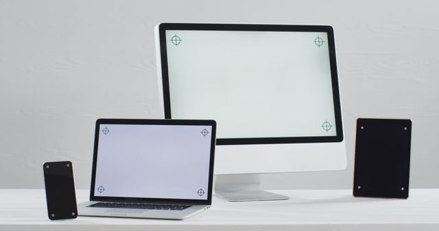 Modern workspace with a smartphone, laptop, tablet, and computer monitor on white desk. Keywords: workspace, electronic devices, smartphone, laptop, tablet, computer monitor, white desk, technology, modern. Ideal for illustrating technology setups, remote working environments, IT services, and digital lifestyle concepts.
