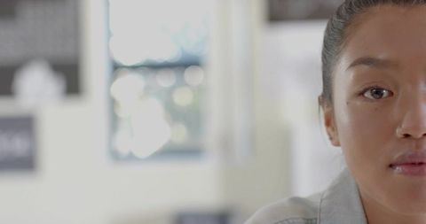 Contemplating woman in denim jacket gazing right with soft window bokeh and copy space