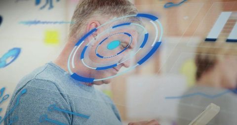 Mature professional holding tablet displaying futuristic HUD overlay in tech workspace